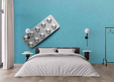 Pills in silver aluminum blister packaging on blue background. Pharmacy products. Wall mural