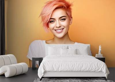 young woman with a short fashionable haircut, peach colored hair, wearing a white T-shirt posing, looking at the camera on a studio peach background Wall mural