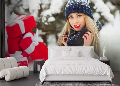 Beautiful woman with christmas presents on a winter background. Cheerful girl on the wooden background. Wall mural