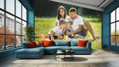 Cheerful family having picnic. Parents having dinner with their kids outdoors. Wall mural