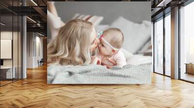 Young mother with her little cute baby daughter. Little baby girl and her mom. Mama with her child indoor. Wall mural