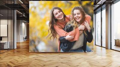 Young pretty girls having fun outdoors in autumn background. Cheerful friends in the fall time Wall mural