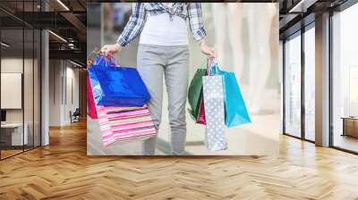 Young woman holding shopping bags near the shopping mall. Female on background with sale banner. Wall mural