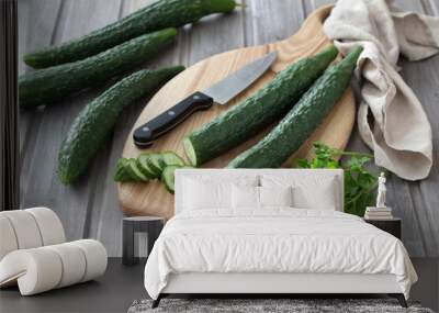 Long Chinese cucumbers on a cutting board while slicing salad. wood background. selective focus Wall mural