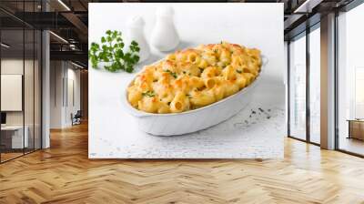 Mac and cheese, baked American pasta in cheese sauce decorated with parsley in a baking dish on a light gray background. Delicious homemade food Wall mural