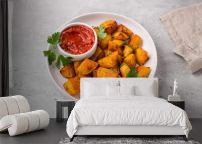 Traditional Spanish potato, patatas bravas with smoked paprika, spicy tomato sauce and parsley in a white bowl on gray stone background, top view. Delicious homemade food Wall mural