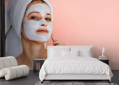 Beautiful young woman with facial mask on her face. Skin care and treatment, spa, natural beauty and cosmetology concept. Wall mural