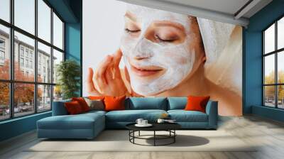 Beautiful young woman with facial mask on her face. Skin care and treatment, spa, natural beauty and cosmetology concept. Wall mural