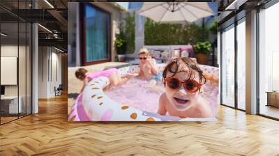 excited kids having fun in inflatable swimming pool at home patio at sunny summer day Wall mural