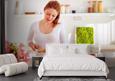 happy young woman preparing tasty snacks at the kitchen table in the morning light Wall mural