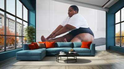 young plus size woman does stretching exercises on sport mat at home, muscules warm-ups Wall mural