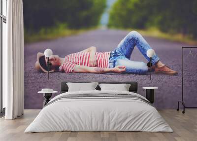 young stylish boy lying on summer road Wall mural