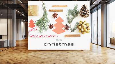 Merry Christmas greeting card. Gift box, ribbon, fir branches, cones, star anise, cinnamon, candy cane and paper christmas tree on white background with congratulation text Wall mural