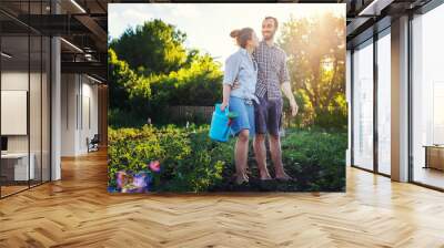 A beautiful young couple of hipsetrs caring for a garden on a bright summer day, eco-friendly lifestyle in the village Wall mural