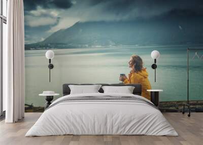 A young beautiful girl is drinking tea on the shore of the fjord, a trip to Norway, the Nordic beauty Wall mural