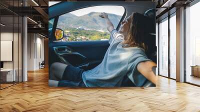 A young woman enjoying a car trip in the passenger seat. Vacations and summer travel concept Wall mural