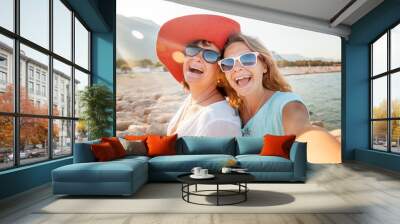 An attractive middle-aged woman with her adult daughter doing selfie on the beach, vacation and travel, cruise and sea Wall mural