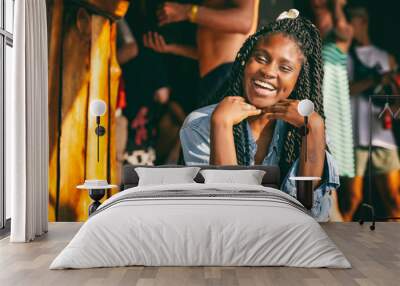 Charming beautiful young african american girl woman with black pigtails with piercings on her face sitting at a bar during a party Wall mural