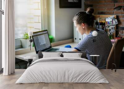 girl student freelancer working with laptop at home by the window, education and remote work, progra Wall mural