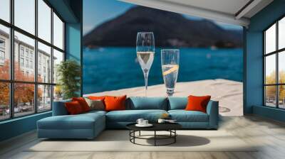 Glasses with cold drinks, a glass of champagne and a glass with a cocktail on a cafe table overlooking the lake and mountains Wall mural