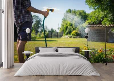 Hipster young man watering plants in a country house, summer and garden care Wall mural