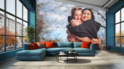 Multiethnic friendship and support concept, two young women a european and an asian sincerely hugging outdoor Wall mural