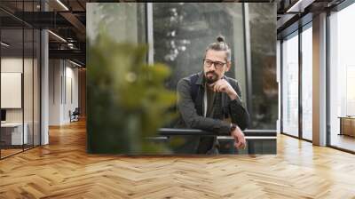 Portrait of a young adult Caucasian attractive man in glasses with a beard outdoors Wall mural