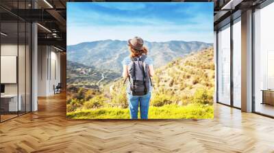 Wanderlust and travel concept. stylish traveler woman in hat looking at mountains. hipster girl traveling on top of mountain, looking in front. space for text. atmospheric moment Wall mural