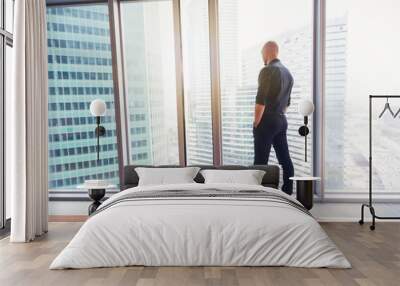 Young attractive stylish bald man in a business suit in his office in a skyscraper, business, finance, success Wall mural