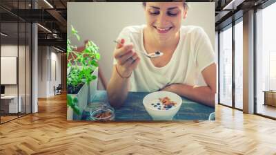 Young beautiful girl woman eating yogurt with flakes and berries for breakfast, healthy food, summer berries, diet Wall mural