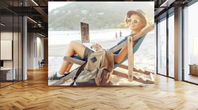 Young beautiful woman hipster traveler freelancer with laptop on the seashore. Business and vacation concept Wall mural