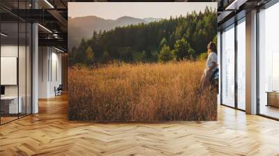 Young beautiful woman traveler enjoying the sunset in the mountains while traveling by car Wall mural