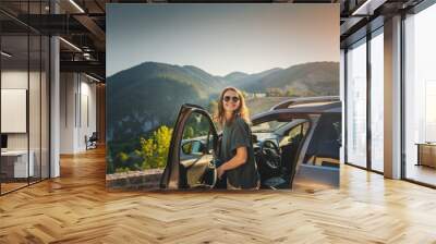 Young beautiful woman traveling by car in the mountains, summer vacation and adventure Wall mural