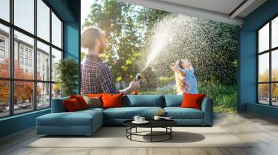 young happy beautiful couple hosing in the garden, summer happiness and love concept, poured water from a garden hose of a spray Wall mural