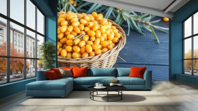 Basket filled with fresh sea buckthorn berries on dark wooden table with green leaves Wall mural