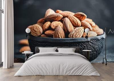   A bowl of almonds rests atop a black countertop, adjacent to a mound of almonds Wall mural