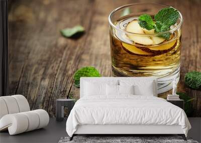   A clear picture of an ice tea glass with mint leaves on a wooden table surrounded by some mint Wall mural