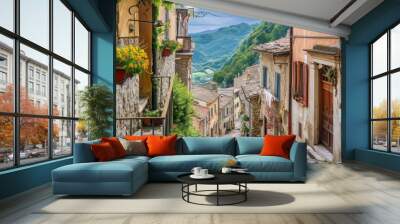  a cobblestone street in a small village with a view of a mountain range in the distance and flowers in the window boxes on either side of the street. Wall mural