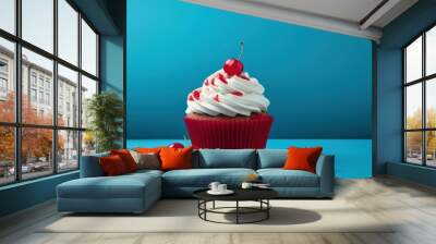  a cupcake with white frosting and cherries on a blue surface with two cherries on the side of the cupcake and two cherries on the side of the cupcake. Wall mural