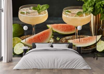   A picture of two glasses filled with watermelon and a pitcher of watermelon alongside slices of lime Wall mural