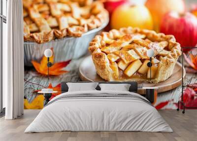   A pie resting atop a wooden table alongside a mound of leaves and an apple pie on a dish Wall mural