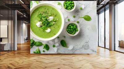   Green pea soup in a bowl with mint garnish and surrounded by small bowls of green peas on a white surface Wall mural