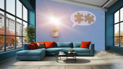 A light bulb, an oval for text, two puzzle pieces on a blue background. Business creative ideas. Wall mural