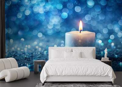 A single candle burning against a dreamy, sparkling blue backdrop creates a peaceful and tranquil atmosphere Wall mural