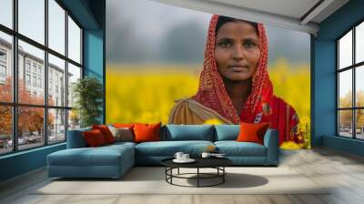 An indian female farmer working in a field of yellow  mustard flowers. Woman mustard  flower farmer at her flower field collecting flower. Wall mural