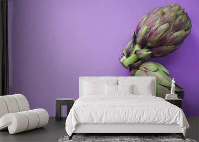 Two artichokes on a purple surface. A photo taken from above. Wall mural