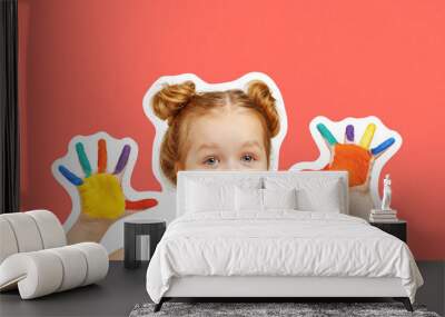 Cheerful little girl child shows hands painted with paint. Orange background, portrait Wall mural