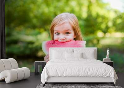 Child eating watermelon in the garden. Kids eat fruit outdoors. Healthy snack for children. 2 years old girl enjoying watermelon. Wall mural