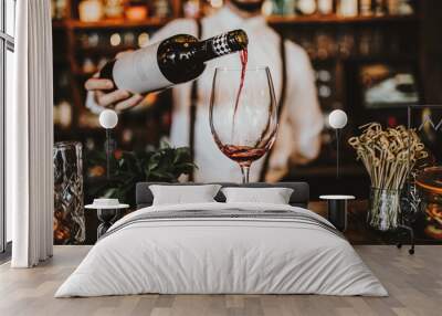 Close up shot of a bartender pouring red wine into a glass. Hospitality, beverage and wine concept. Wall mural