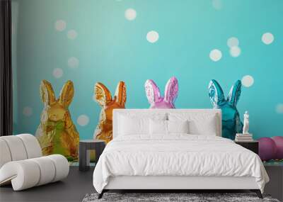 Easter chocolate bunnies in multi-colored golden wrappers on a blue background Wall mural